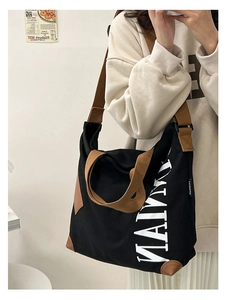 Détail du grand sac cabas en toile noire avec anses marron et impression de lettres blanches
