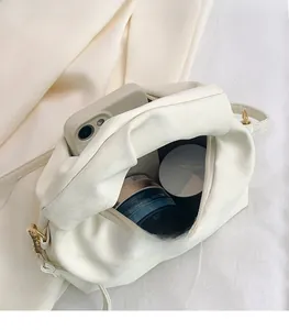 Internal view of cream pleated crossbody bag showing space for phone and makeup