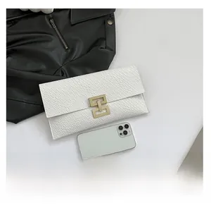 Close-up of white crocodile pattern envelope clutch with elegant gold metal buckle