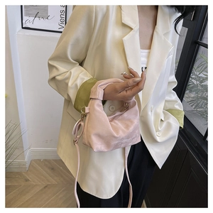 Detail of pink pleated crossbody bag in soft suede-like texture styled with chic blazer