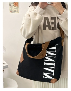 Gros plan du sac fourre-tout en toile noir et marron avec surpiqûres et logo TAIMNI
