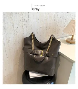 Détail d'un grand sac cabas gris avec sangles décoratives et chaîne métallique dorée