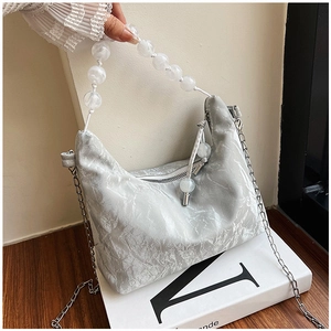 Detail of silver pleated texture handbag with matte white beaded handle and silver chain