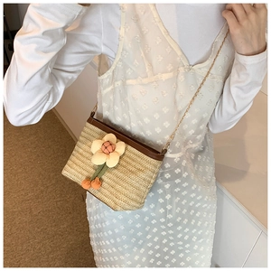 Vue détaillée du sac seau en paille tressée avec motif floral et bandoulière en chaîne dorée