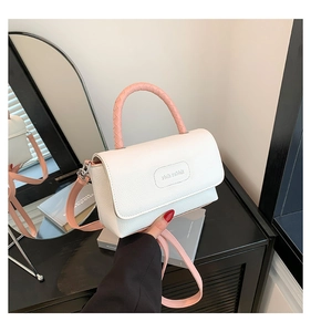 Détail du sac à main en cuir blanc avec poignée tressée rose et rabat marqué au relief