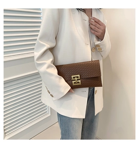 Detail of brown envelope clutch bag featuring snake-pattern texture and gold metal lock