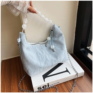 Detail of light blue hobo bag with marble bead handle and silver metal chain strap