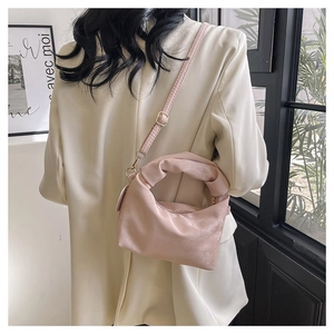 Detail of light pink ruched handbag featuring a knotted handle and golden metal buckle