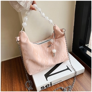 Detail of light pink pleated handbag featuring white marble beaded handle and silver chain