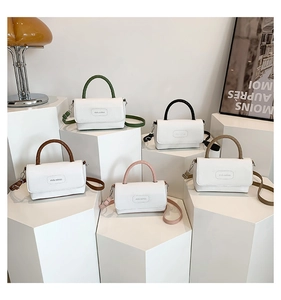Détails des mini sacs à main bicolores disposés sur des supports géométriques blancs