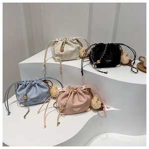 Detail view of four trendy drawstring bucket bags with chains and plush bear charms