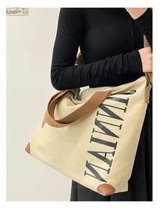 Gros plan d'un sac cabas en toile crème avec coins en cuir marron et bandoulière robuste