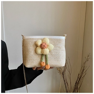 Vue détaillée du sac seau en paille avec fleur 3D décorative et bandoulière en chaîne dorée