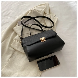 Detail of black faux leather handbag with crocodile pattern flap and gold metal buckle