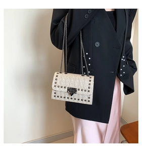 Détail d'un sac bandoulière beige tissé avec clous argentés et chaîne sur un mannequin