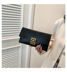 Detail of black crocodile texture envelope clutch with a gold geometric metal clasp