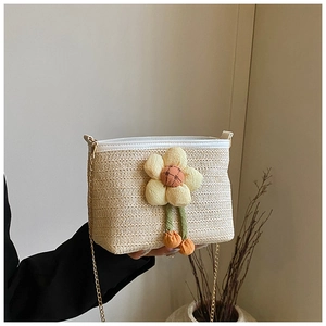 Détail d'un sac seau en paille tressée avec grande fleur en peluche jaune et chaîne