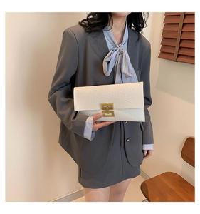 Close-up of white crocodile pattern envelope clutch with gold H-shaped metal buckle