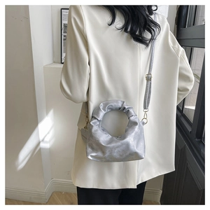 Detail of silver pleated handbag featuring metallic texture and round handle design
