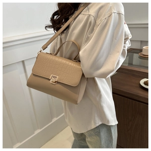 Detail of beige crossbody bag featuring crocodile texture flap and metal square lock closure