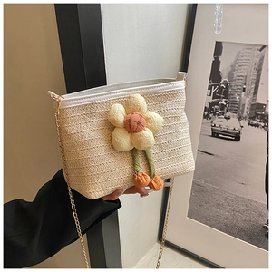 Détail du sac seau en paille tressée avec breloque fleurie et chaîne dorée