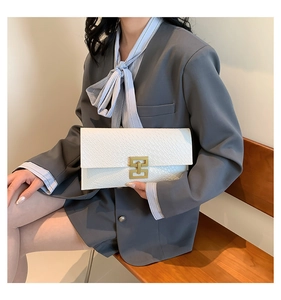 Detail of white envelope clutch with faux crocodile texture and gold metal buckle