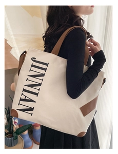 Détail du sac cabas en toile avec garniture en cuir marron et logo JINNIAN décontracté