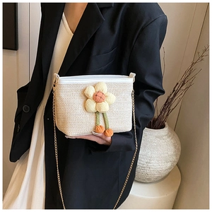 Détail du sac bandoulière en paille tressée avec fleur et bandoulière chaîne dorée