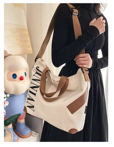 Mannequin portant un grand sac fourre-tout en toile crème avec logo JINNIAN et lanières