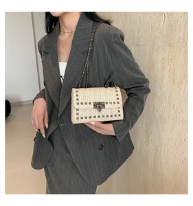 Détail du sac à bandoulière tressé beige avec clous en métal et chaîne élégante