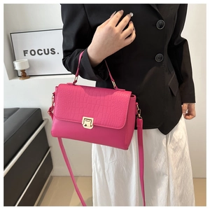 Detail of fuchsia crossbody bag with crocodile embossed flap and gold twist lock closure
