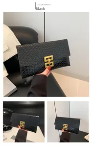 Detail of black envelope clutch with woven texture and gold geometric metal buckle
