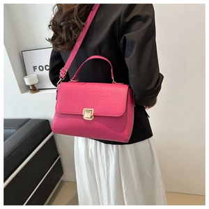 Detail of pink croc-embossed bag with gold lock and metal handle on a fashion model
