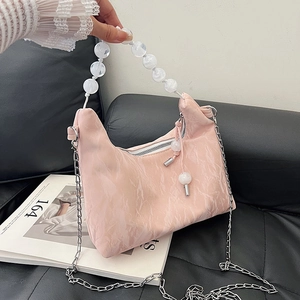 Pink marble pattern cloud bag with beaded handle and silver chain on leather sofa