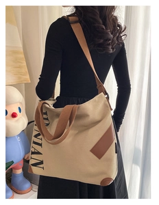 Sac fourre-tout en toile beige avec sangles brunes porté par un mannequin en intérieur