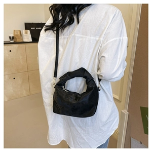 Detail of black pleated crossbody bag with decorative knot handle and soft matte finish