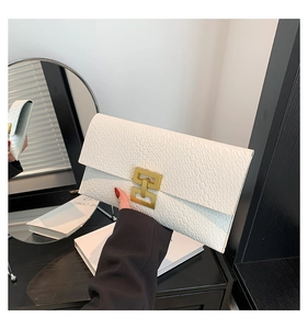 Close-up of white embossed leather envelope clutch with a luxury gold geometric clasp