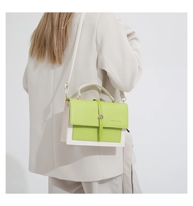 Petit sac à main bicolore vert et blanc avec boucle magnétique porté par modèle