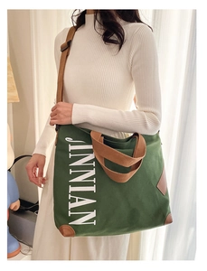 Détail du sac cabas en toile verte avec lettrage blanc et coins renforcés en cuir