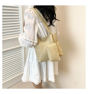 Détail d'un ensemble de sacs cabas en paille tissés main portés à l'épaule en intérieur