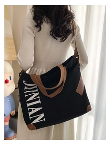 Détail du grand sac cabas en toile avec finitions en cuir marron et texte JINIAN