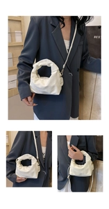 Detail of off-white pleated handbag with soft texture and elegant metal ring handle