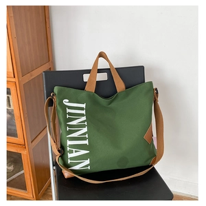Détail du sac fourre-tout en toile vert foncé avec logo JINNIAN et bandoulière marron