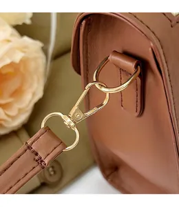 Close-up of golden metal hooks and detachable brown leather strap on a rhombic bag