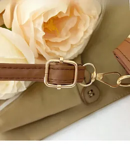 Close-up of adjustable brown leather shoulder strap with gold metal buckle and spring hook