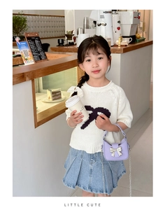 Girl wearing a white bow knit top with a blue denim skirt and a purple mini handbag