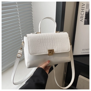 Detail of the white leather tote bag featuring a crocodile pattern flap and golden hardware