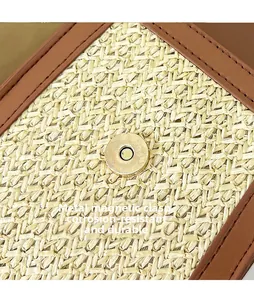 Detailed macro view of the gold magnetic buckle on a woven straw shoulder bag