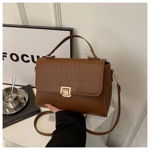 Detail showing brown faux leather texture with crocodile embossed pattern and gold buckle