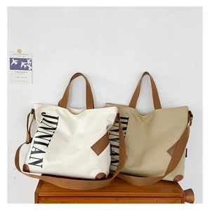 Détails des cabas en toile avec logo JINNIAN, coins en cuir et bandoulières brunes